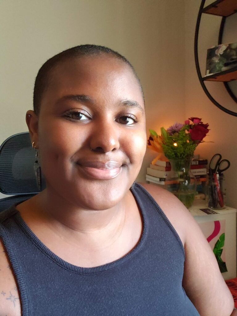 Kiana Elkins peer advising A photo of a woman wearinga black top, smiling, with flowers in the background